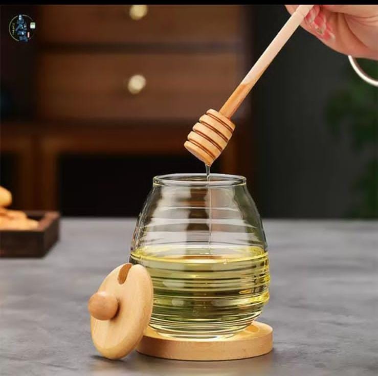 Glass honey storage jar with wooden lid and stirring stick