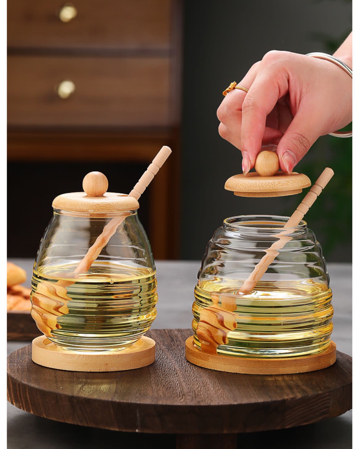 Glass honey storage jar with wooden lid and stirring stick