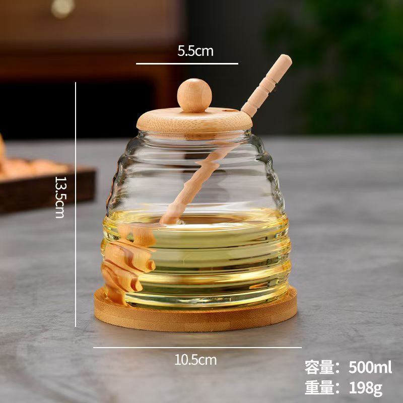 Glass honey storage jar with wooden lid and stirring stick